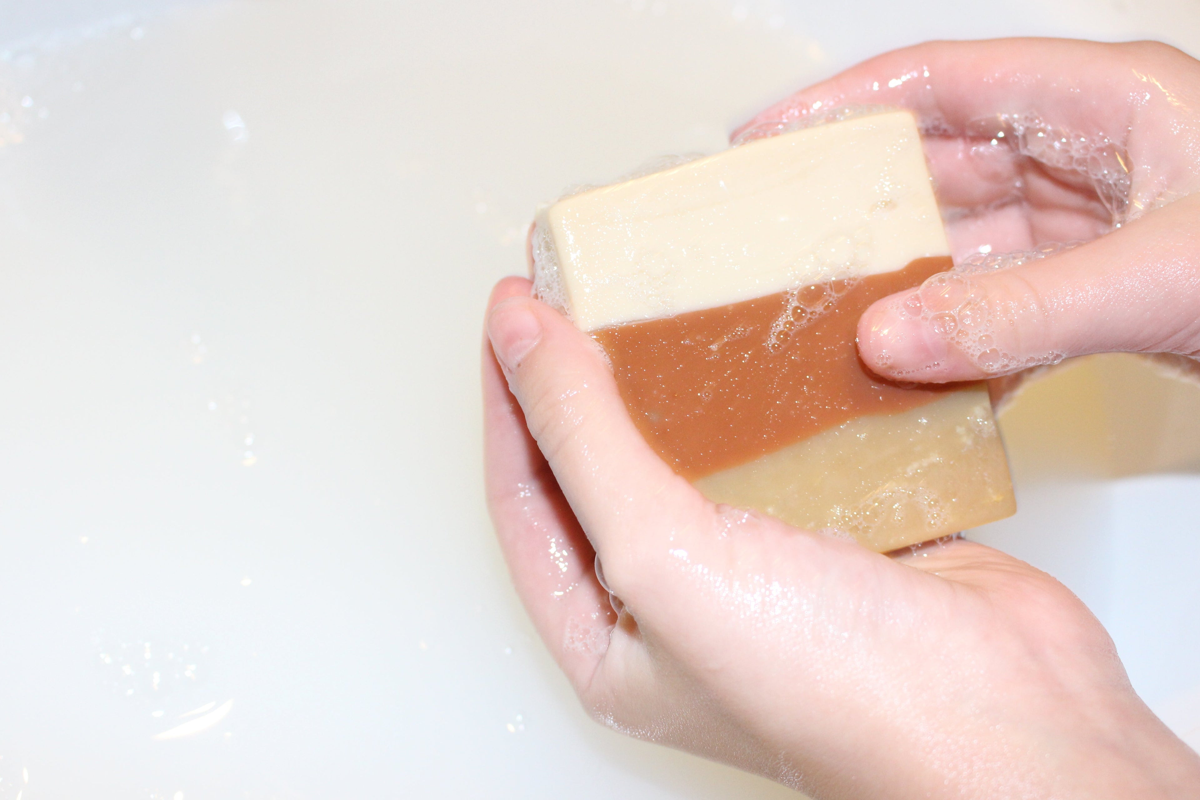 Hand holding a bar of soap over a white sink